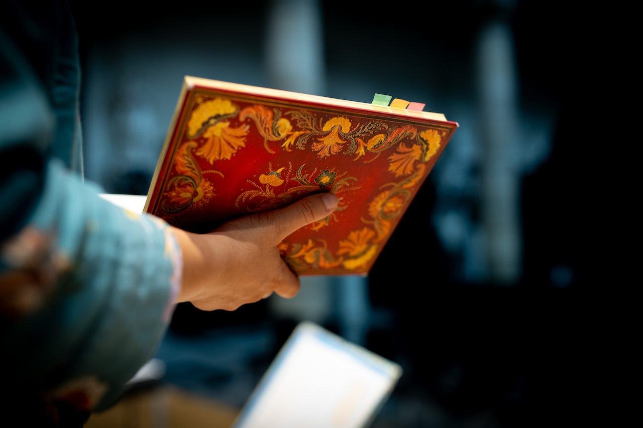 Singer holding book with detailed cover Laus Polyphoniae (2025)